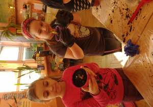 Dziewczynki pokazują posadzone w doniczki cebule na szczypiorek
